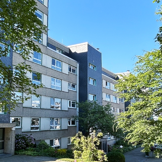 Banner eines Mehrfamilenhauses mit Bäumen davor in Stadt Essen