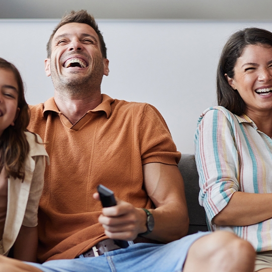 4-köpfige Familie glücklich auf der Couch am Fernsehen schauen.