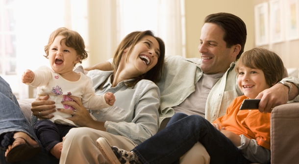 Eine Familie lacht auf der Couch.
