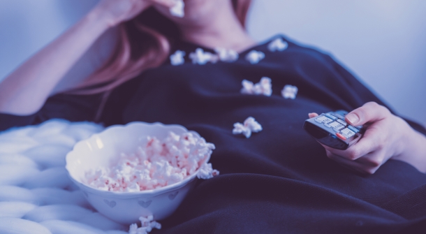 Jemand schaut fern und isst Popcorn.