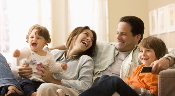 Eine Familie lacht auf der Couch.