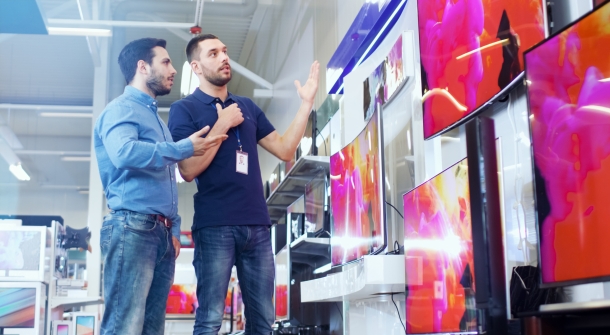 Ein Kunde mit einem Berater beim Fernseherkauf.